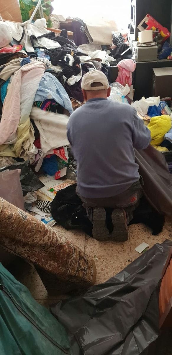 עובד כורע ליד ערימה גדולה של בגדים וטקסטיל וממיין אותם