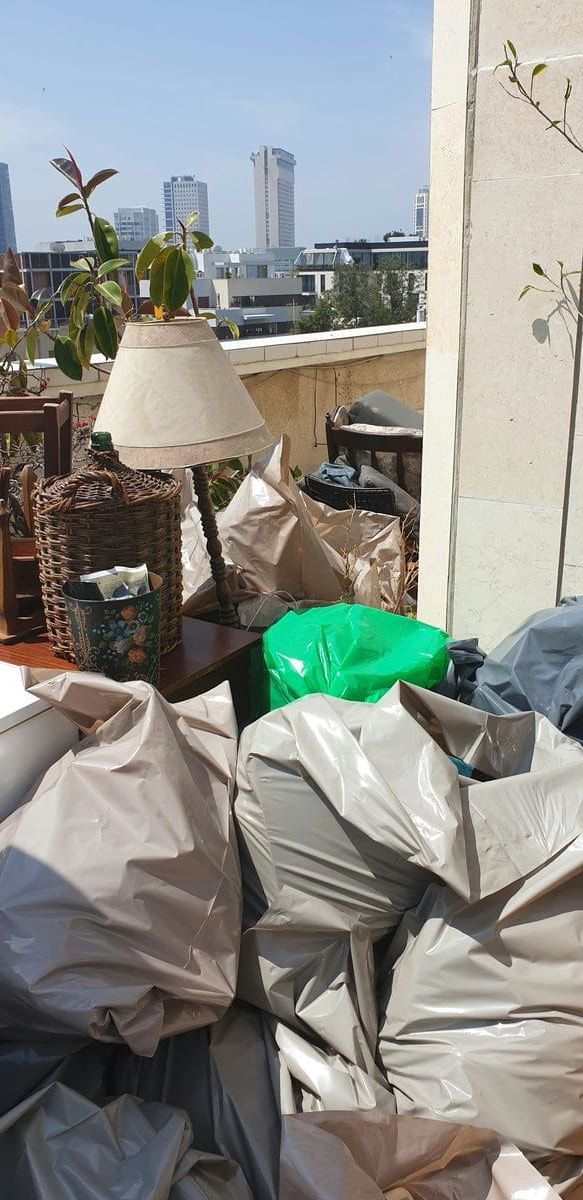 מרפסת גג עם נוף לעיר, עמוסה בשקיות גדולות, מנורה וסל קש