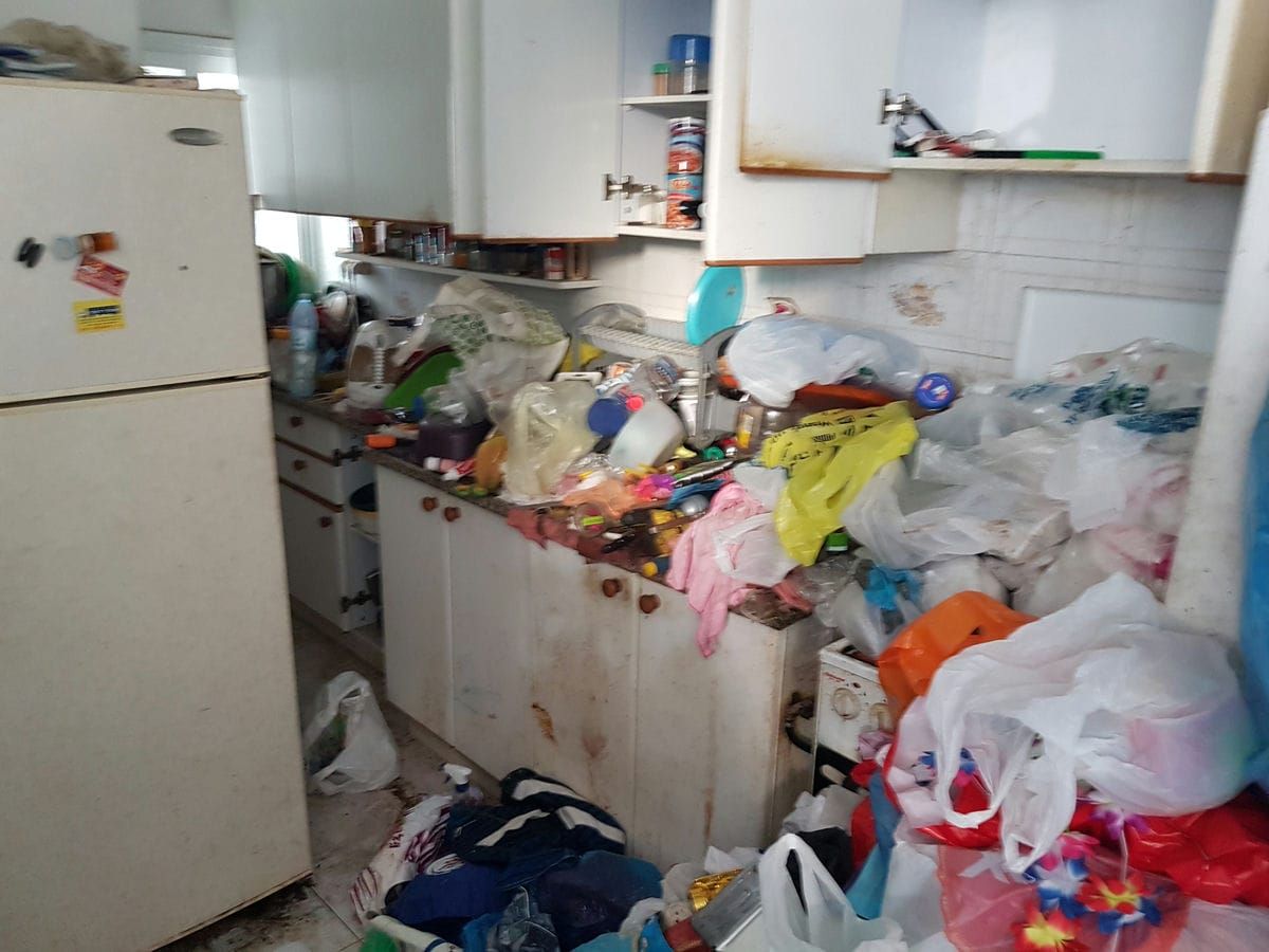 מטבח שהשיש והרצפה שלו עמוסים בשקיות, בקבוקים וכלים, ודלתות הארונות פתוחות