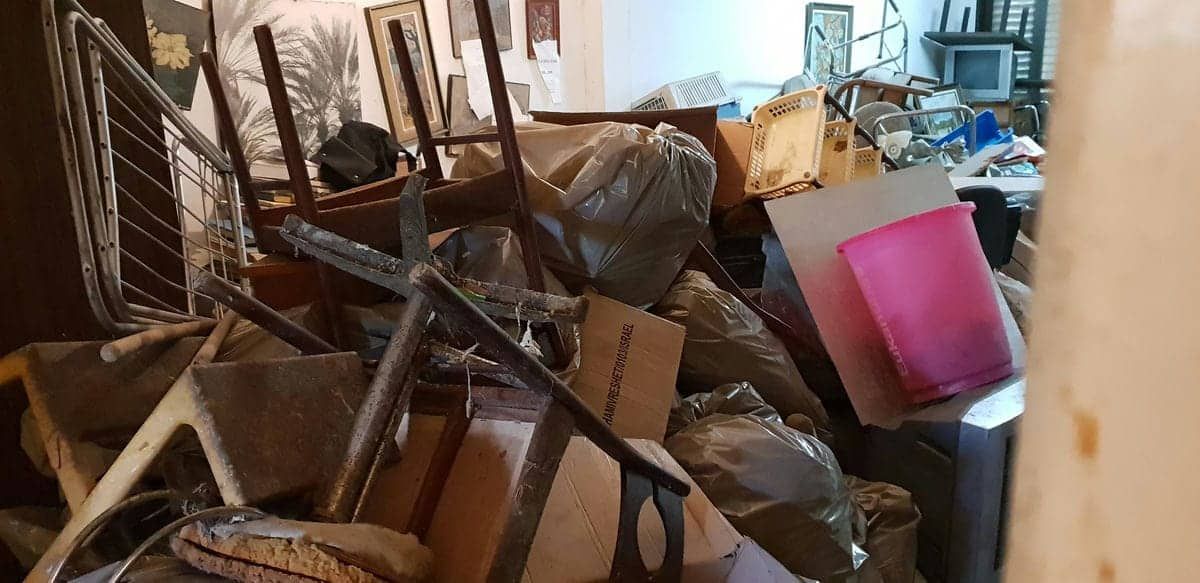 חדר עמוס ברהיטים ישנים, שקיות אשפה וארגזים הממתינים לפינוי